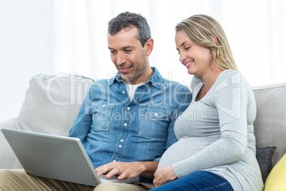 Couple sitting together and using laptop