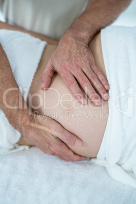 Pregnant woman receiving a stomach massage from masseur