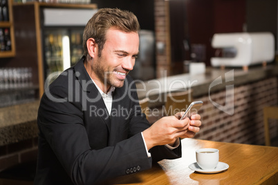 Handsome man looking at smartphone and having a coffee