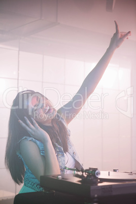 Pretty female DJ waving her hand while listening music