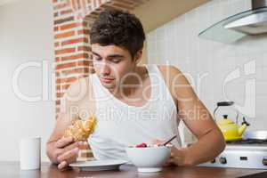 Young man having breakfast in kitchen