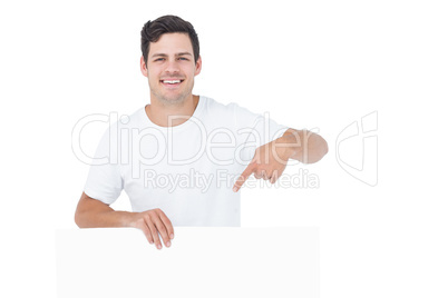 Handsome man pointing a white poster