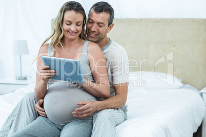 Expecting couple sitting on bed