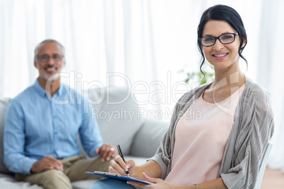 Female doctor writing on clipboard while consulting a man