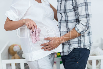 Pregnant couple holding baby shoes