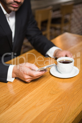 Businessman using smartphone and having coffee