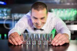 Bartender placing shot glasses on bar counter