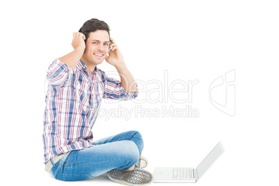 Man with headphones sitting on the floor using laptop