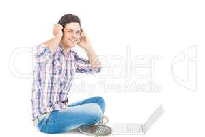 Man with headphones sitting on the floor using laptop