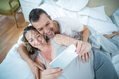 Expecting couple lying on bed