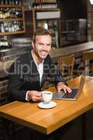 Handsome man using laptop and having a coffee