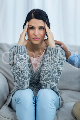 Worried pregnant woman sitting on sofa