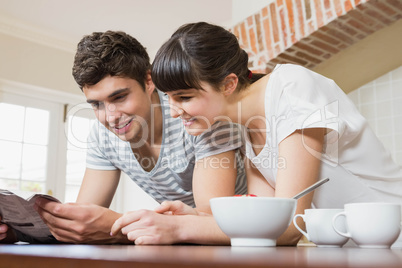 Young couple reading book while having breakfast