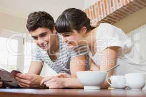 Young couple reading book while having breakfast