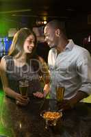 Couple looking at each other while having beer at bar counter