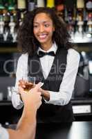 Female barmaid serving a glass of whiskey