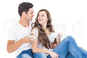 Young couple sitting on floor drinking coffee
