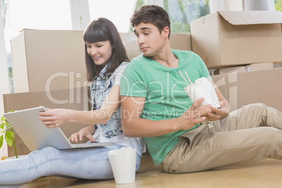 Young couple eating noodle and using laptop