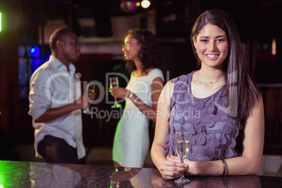 Young woman having champagne in bar and her friends talking