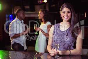 Young woman having champagne in bar and her friends talking