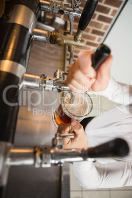 Handsome barman pouring a pint of beer