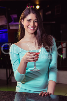 Portrait of young woman having a cocktail at bar counter