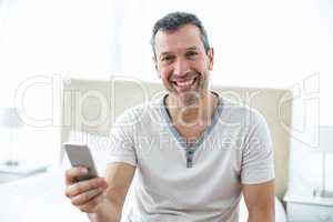 Man using smartphone in bedroom