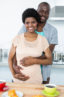 Pregnant couple embracing while having breakfast