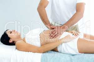 Pregnant woman receiving a stomach massage from masseur