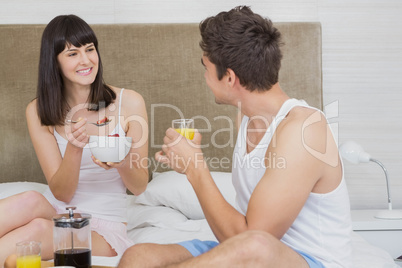 Young couple having breakfast on bed