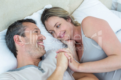 Expecting couple lying on bed and chatting