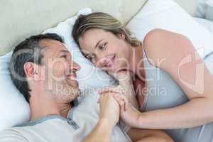 Expecting couple lying on bed and chatting