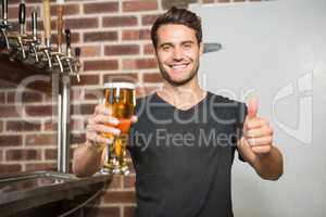 Handsome man holding a pint of beer with thumbs up