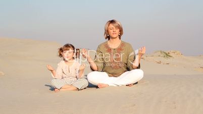mother and daughter meditating in desert