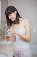 Beautiful woman putting pill in to a glass of water