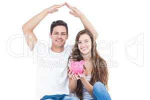 Young couple sitting on floor with piggy bank