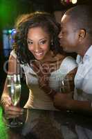 Man kissing a woman while having champagne at bar counter