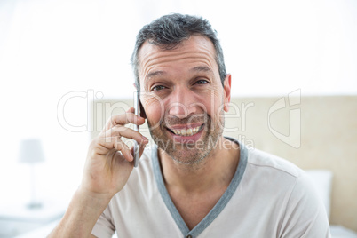 Man talking on smartphone in bedroom