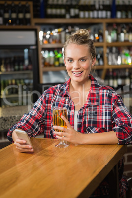 Pretty woman using smartphone and having a beer