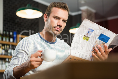 Handsome man reading newspaper and having a coffee