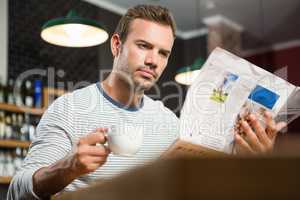 Handsome man reading newspaper and having a coffee