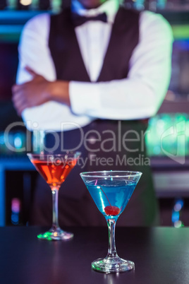 Blue and orange glasses of cocktail on bar counter