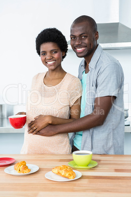 Pregnant couple having breakfast in kitchen