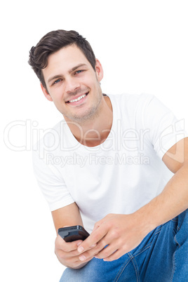 Handsome man crouching using a smartphone