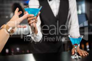 Bartender serving blue cocktail at bar counter