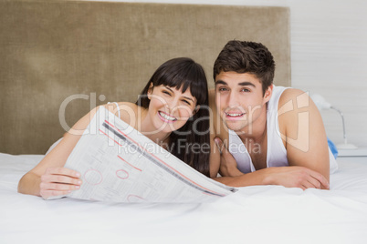 Couple reading newspaper on bed