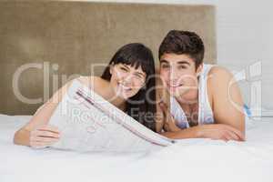 Couple reading newspaper on bed