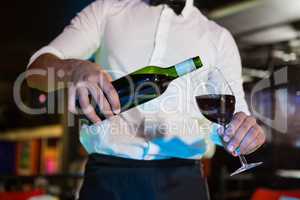 Waiter pouring wine in a glass