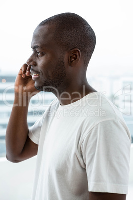 Man talking on mobile phone near window