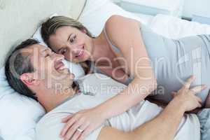 Expecting couple lying on bed and chatting